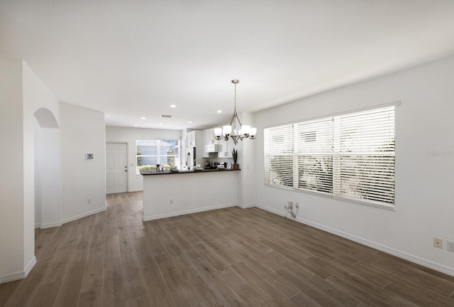 unfurnished dining area with recessed lighting, wood finished floors, and a notable chandelier