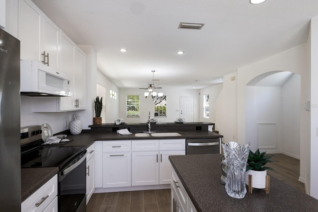 kitchen with a sink, dark wood finished floors, a peninsula, and stainless steel appliances