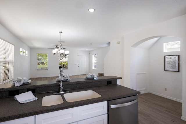 kitchen featuring stainless steel dishwasher, dark countertops, a sink, and dark wood-type flooring