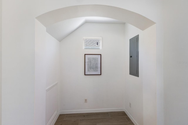 bonus room featuring electric panel, arched walkways, vaulted ceiling, wood finished floors, and baseboards