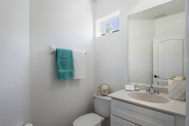 half bathroom featuring vanity, visible vents, and toilet