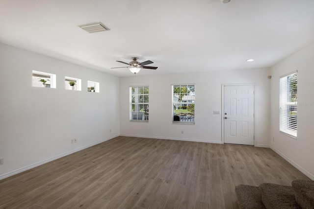 interior space featuring baseboards, visible vents, wood finished floors, and a wealth of natural light