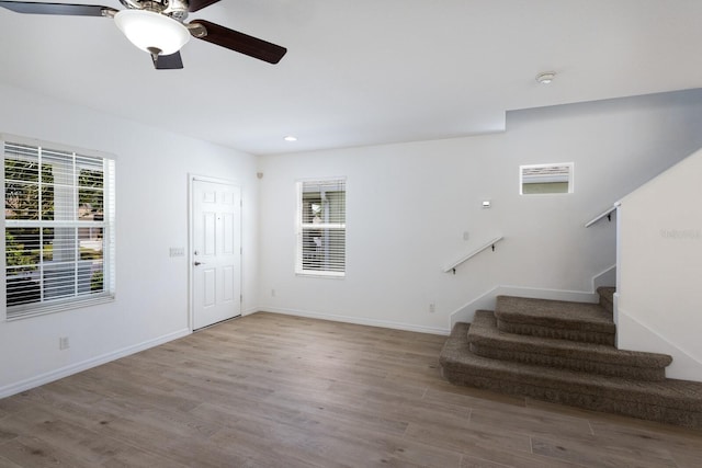 foyer entrance featuring plenty of natural light, ceiling fan, wood finished floors, and stairway
