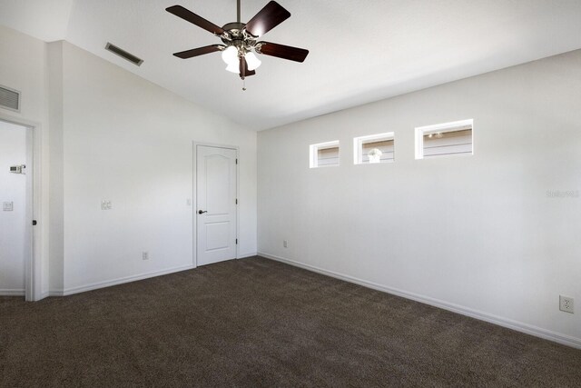 unfurnished room with visible vents, baseboards, dark carpet, a ceiling fan, and vaulted ceiling