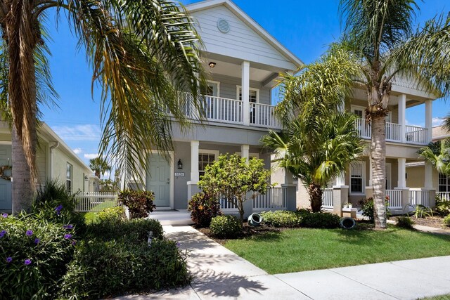 view of front of home featuring a balcony, covered porch, and a front yard