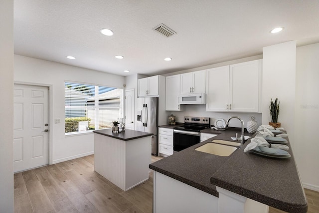 5526 River Sound Ter, Bradenton, FL 34208 - kitchen featuring appliances with stainless steel finishes, a sink, a kitchen island, light wood-style floors, and dark countertops