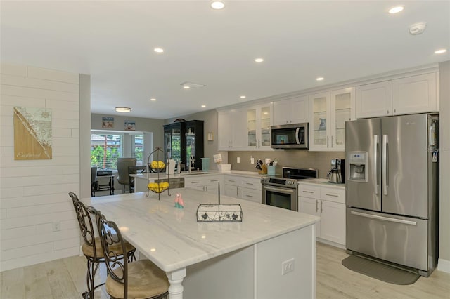 kitchen featuring white cabinets, a breakfast bar area, appliances with stainless steel finishes, and light wood-style floors