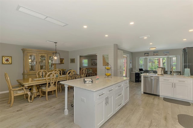 kitchen featuring stainless steel dishwasher, a sink, light wood-style floors, and white cabinetry