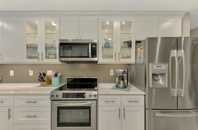 kitchen featuring light countertops, decorative backsplash, white cabinets, and stainless steel appliances