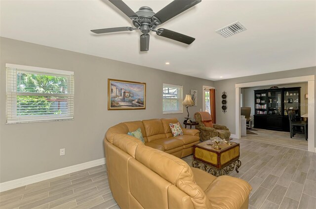 living room featuring wood tiled floor, ceiling fan, visible vents, baseboards, and recessed lighting