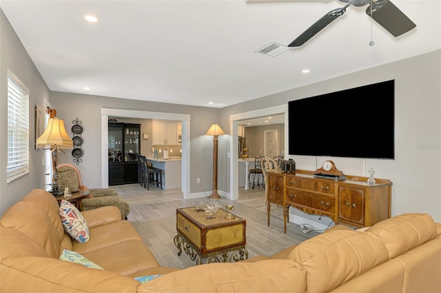 living area with light wood-style floors, a ceiling fan, baseboards, recessed lighting, and visible vents