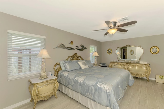 bedroom with baseboards, visible vents, ceiling fan, and light wood-style floors