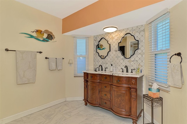 bathroom featuring baseboards, a sink, marble finish floor, and double vanity