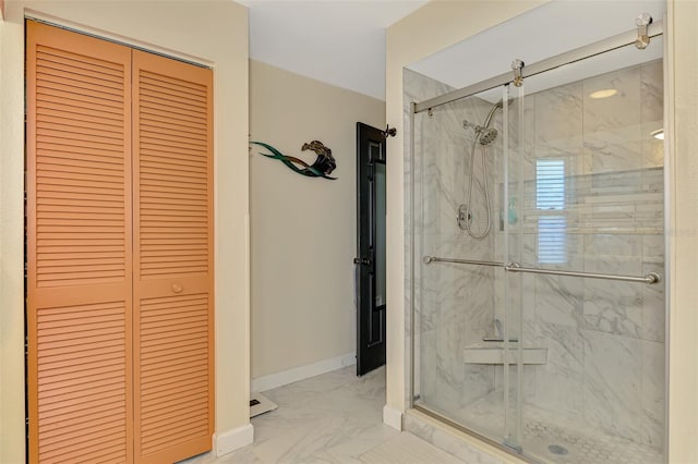 bathroom featuring a stall shower, baseboards, marble finish floor, and a closet