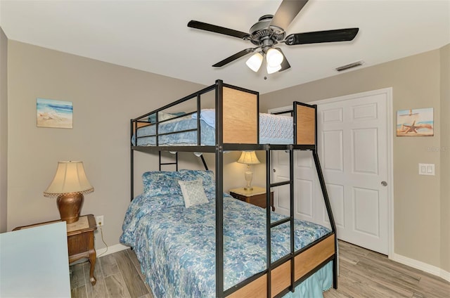 bedroom with baseboards, ceiling fan, wood finished floors, and visible vents
