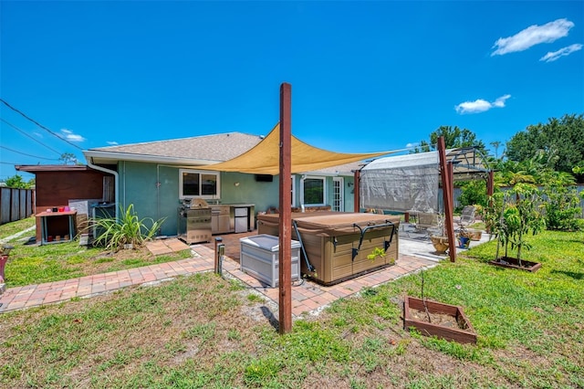 rear view of house with a pergola, stucco siding, a patio area, a hot tub, and a yard