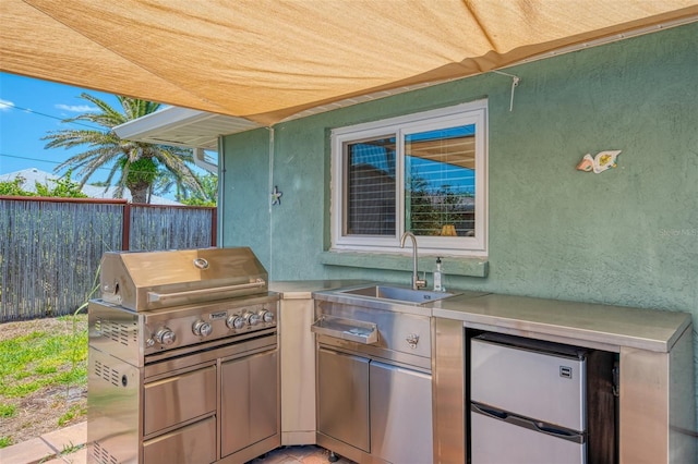 view of patio with fence, a sink, and area for grilling