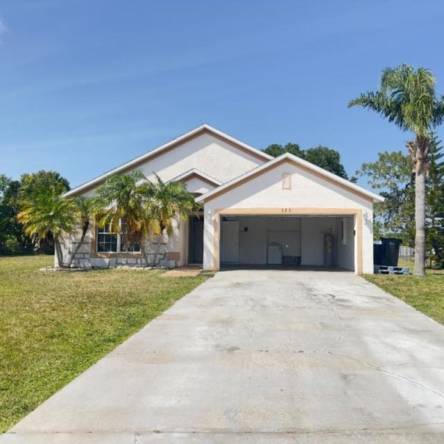 single story home with a garage, stucco siding, a front yard, and concrete driveway