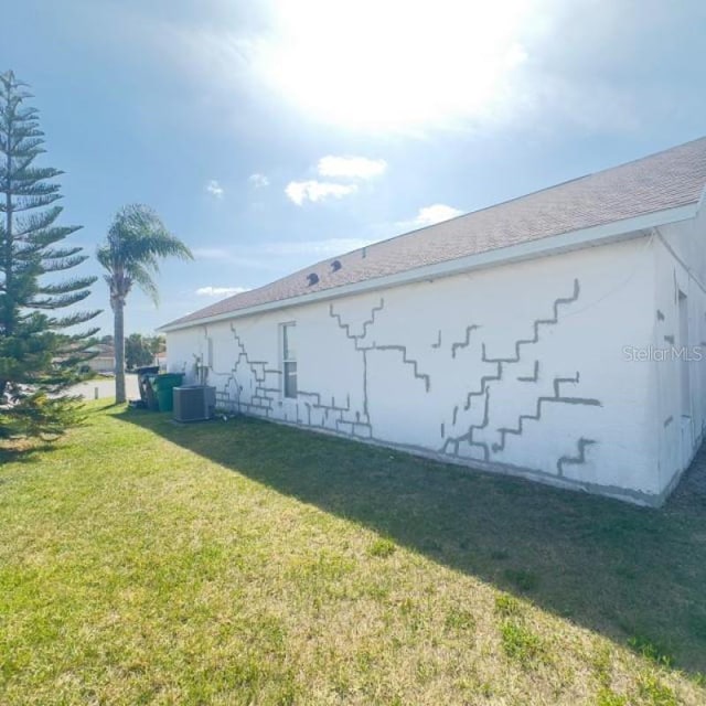 view of side of home with a yard and cooling unit