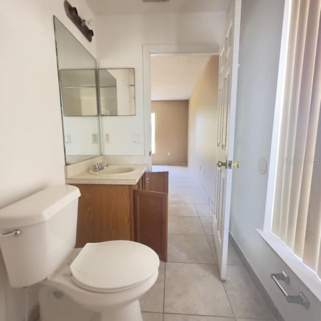 half bath with vanity, tile patterned flooring, and toilet