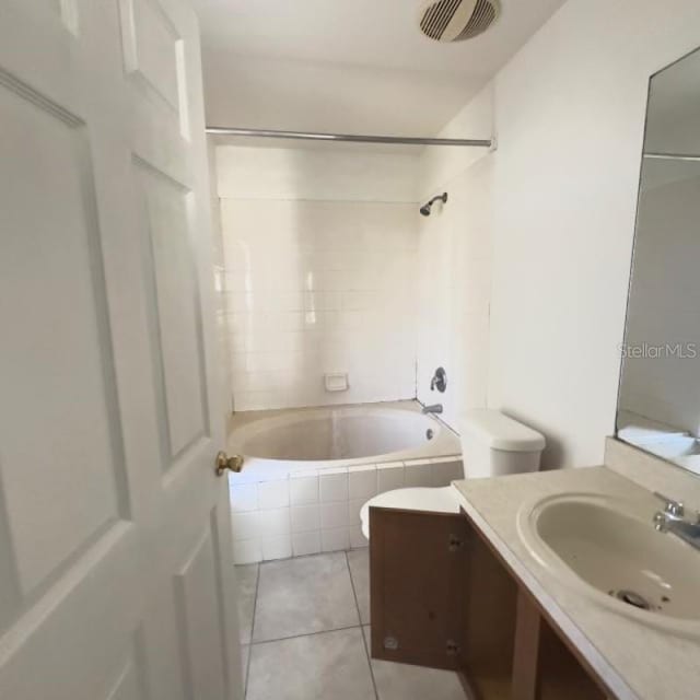 bathroom featuring visible vents, vanity, tile patterned floors, toilet, and tiled shower / bath combo