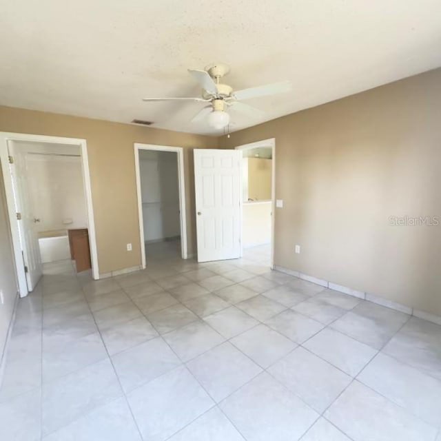unfurnished bedroom with visible vents, baseboards, a closet, a spacious closet, and light tile patterned flooring