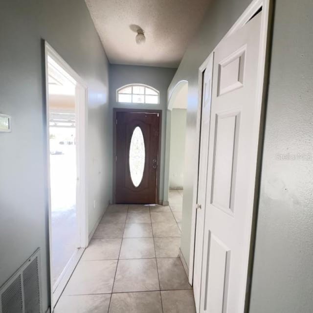 entryway with visible vents, a textured ceiling, and light tile patterned flooring