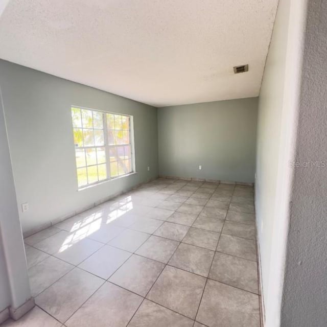 empty room featuring a textured ceiling and light tile patterned floors