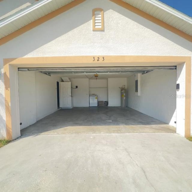 garage with driveway, washer and clothes dryer, and electric water heater