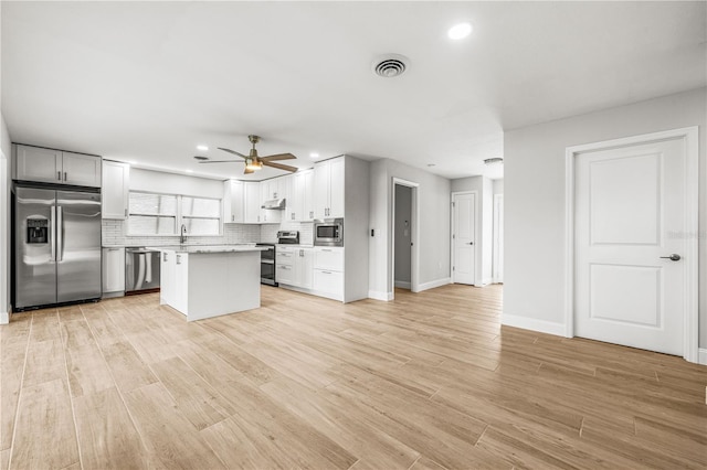1680 Lemon Bay Dr, Venice, FL 34293 - kitchen with stainless steel appliances, ceiling fan, light wood-style floors, decorative backsplash, and light countertops