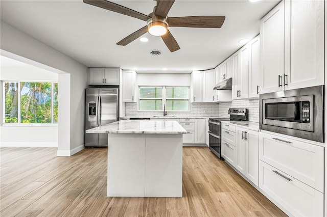 1680 Lemon Bay Dr, Venice, FL 34293 - kitchen featuring appliances with stainless steel finishes, under cabinet range hood, baseboards, a center island, and a sink