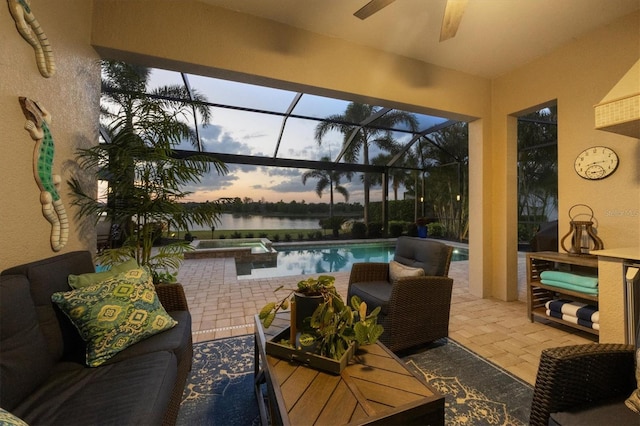 patio terrace at dusk featuring an outdoor pool, a water view, an outdoor living space, a ceiling fan, and glass enclosure