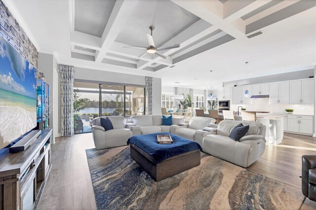 living area with ceiling fan, light wood-style floors, a water view, visible vents, and coffered ceiling