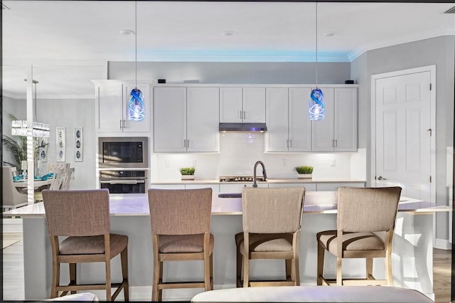 kitchen with hanging light fixtures, light countertops, stainless steel oven, built in microwave, and decorative backsplash
