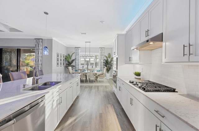 kitchen with under cabinet range hood, white cabinets, a sink, backsplash, and stainless steel appliances