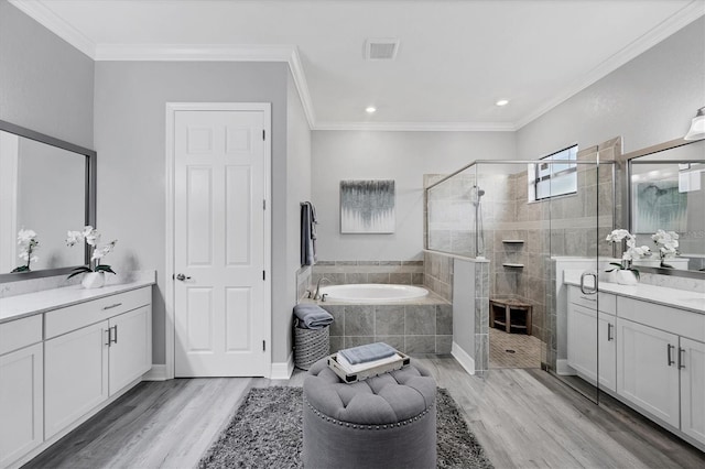 bathroom featuring a garden tub, a stall shower, two vanities, and wood finished floors