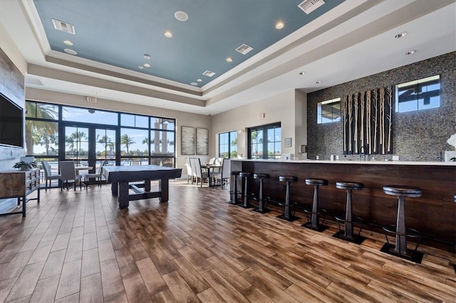 playroom featuring a community bar, a tray ceiling, wood finished floors, and visible vents