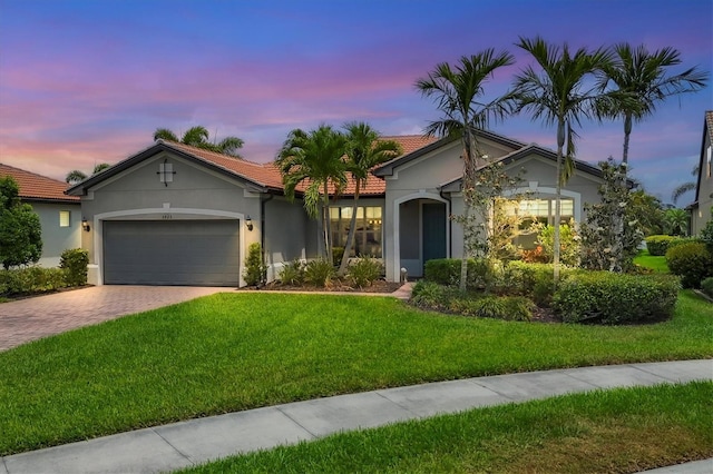 view of front of home with a tile roof, a garage, stucco siding, a front yard, and driveway