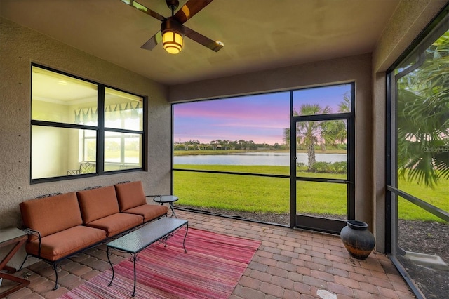 sunroom / solarium with an outdoor living space, a water view, a ceiling fan, and a wealth of natural light