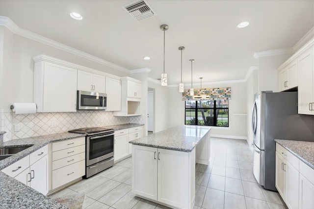 kitchen with backsplash, visible vents, appliances with stainless steel finishes, a center island, and white cabinetry