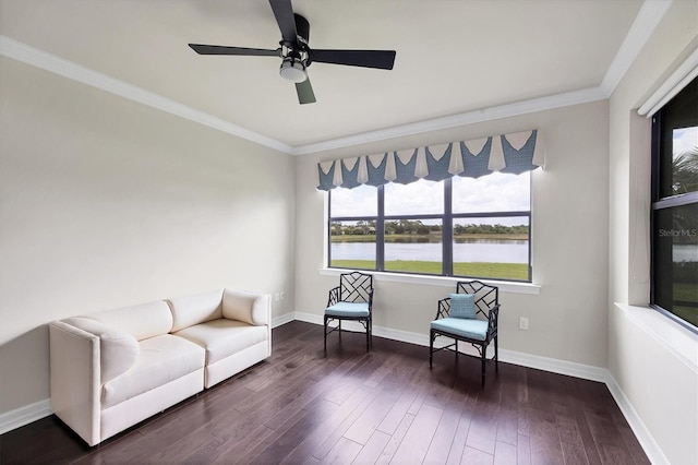 living area with dark wood-style flooring, ceiling fan, baseboards, a water view, and ornamental molding