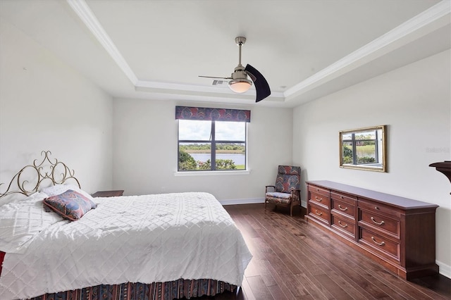 bedroom with a raised ceiling, ornamental molding, dark wood-style floors, and visible vents