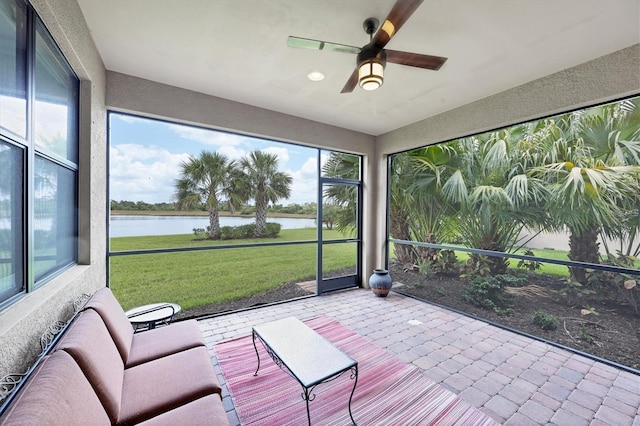 unfurnished sunroom with a healthy amount of sunlight, a water view, and a ceiling fan