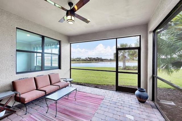 sunroom / solarium featuring plenty of natural light, a ceiling fan, and a water view