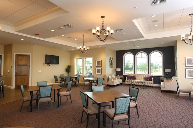 carpeted dining space with a raised ceiling, visible vents, ornamental molding, and a chandelier