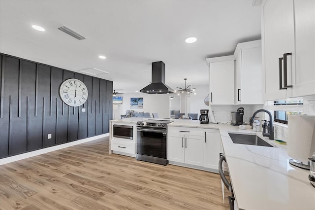 2301 Cass St, Sarasota, FL 34231 - kitchen with white cabinets, appliances with stainless steel finishes, a sink, island range hood, and visible vents