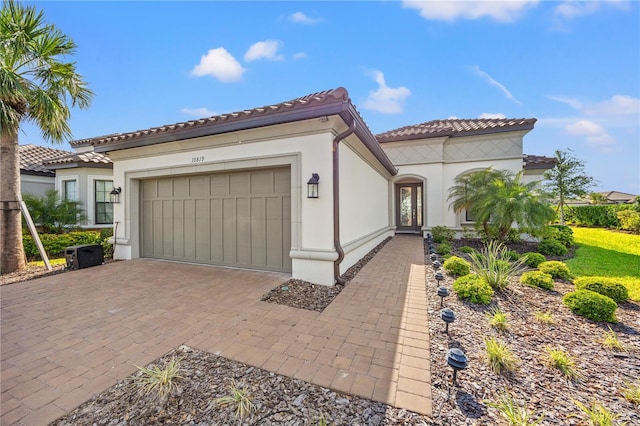 10819 Wicker Park Pl, Palmetto, FL 34221 - mediterranean / spanish-style house with decorative driveway, a garage, stucco siding, and a tile roof