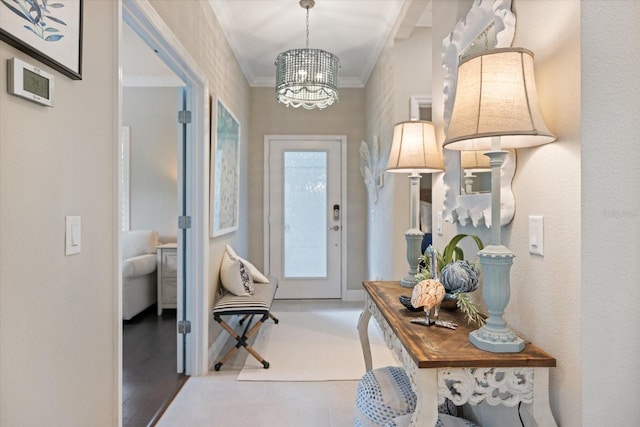 entryway featuring crown molding, baseboards, and an inviting chandelier