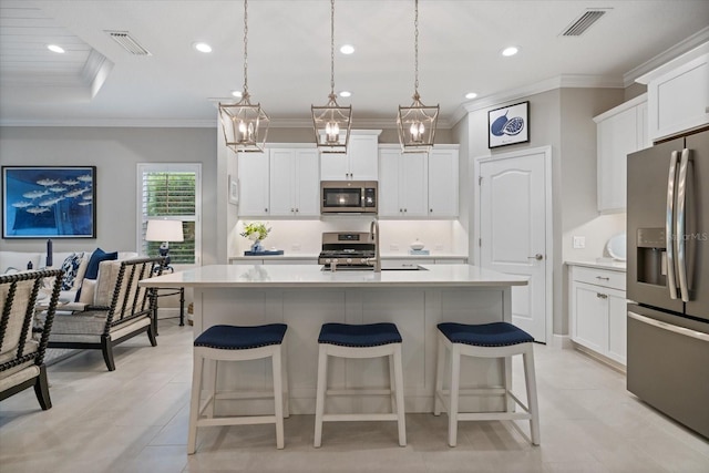 kitchen with visible vents, ornamental molding, an island with sink, a kitchen breakfast bar, and stainless steel appliances