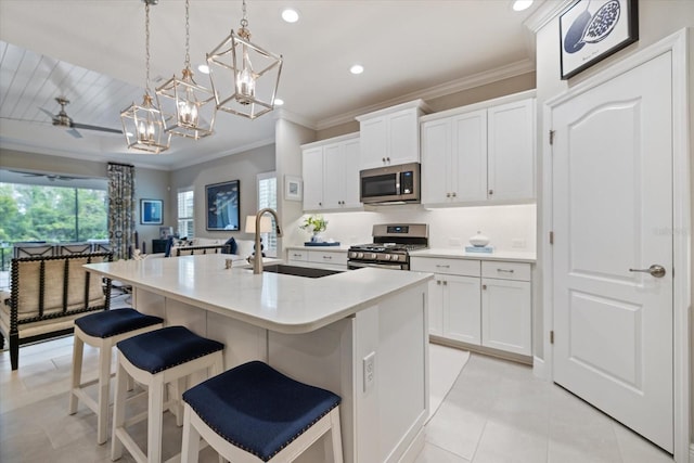 kitchen featuring a kitchen island with sink, light countertops, white cabinets, a sink, and stainless steel appliances